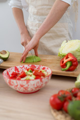 A woman makes a salad of fresh vegetables. Vegetarian, healthy food.