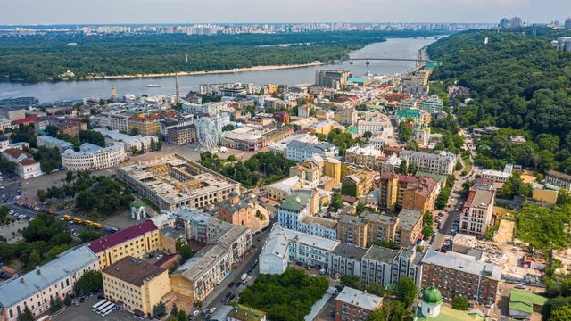 Fly over famous Kiev Podil district at summer. Kontractova square with rotating white ferris wheel. Aerial footage 4k