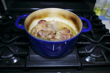 Pork roast cooked in a Dutch oven resting on the stove top.