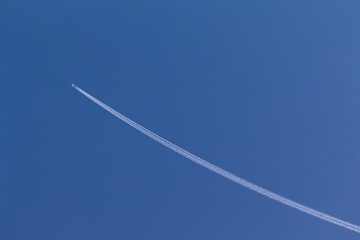The white airplane fly in the sky, jet engine make the white line of smoke in the blue sky, for design about direction symbol.
