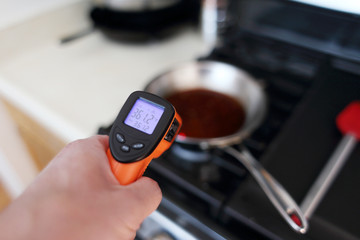 Using a laser temperature gun to check the heat level of a skillet on the stove top.
