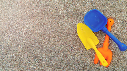 Fototapeta na wymiar Plastic children's toys in the sand. Concept of family vacation. Top view. Space for text.