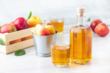 Healthy organic food. Apple cider vinegar in glass bottle and fresh red apples on a light background.