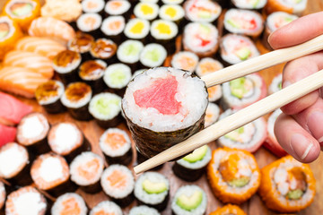 chopsticks with tuna roll over set of sushi
