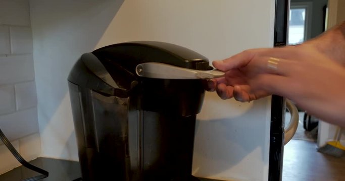 Man using a single serving pod coffee maker to brew a cup of coffee
