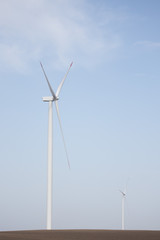 Two wind turbines on agricultural ground with clear sky in background