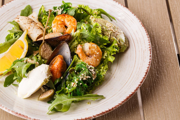 Healthy Salad. Recipe for fresh seafood. Grilled shrimps, mussels and squid, fresh salad lettuce and avocado puree. Healthy Eating. Wooden background