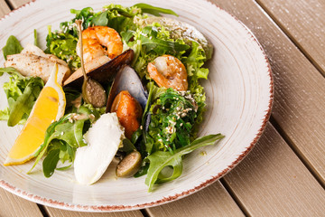Healthy Salad. Recipe for fresh seafood. Grilled shrimps, mussels and squid, fresh salad lettuce and avocado puree. Healthy Eating. Wooden background
