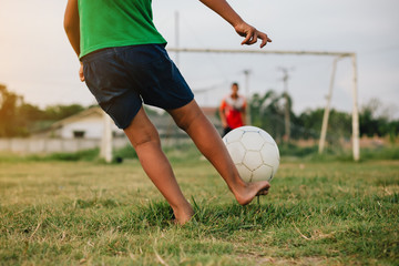action sport outdoors of a group of kids having fun playing soccer football for exercise in community rural area under the twilight sunset sky.
