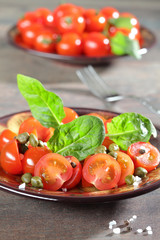 Cherry tomatoes served with basil leaves and capers