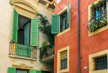  orner in Verona with colored houses, palm trees on the balconies and wooden green shutters on the windows