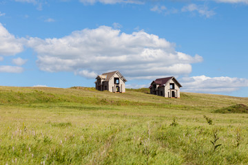 Two unfinished houses on the green field against blue sky