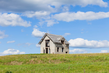 Fototapeta na wymiar unfinished house on the green field against blue sky