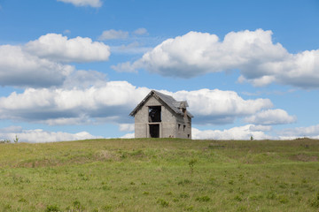 Fototapeta na wymiar unfinished house on the green field against blue sky