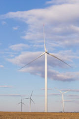 Fototapeta premium Wind turbines on agricultural ground with cloudy sky in background