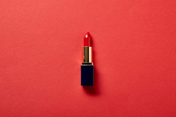 top view of single tube of red lipstick on red - obrazy, fototapety, plakaty