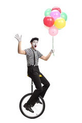 Mime on a unicycle holding a bunch of colorful balloons and waving at the camera