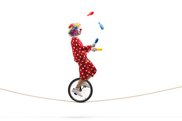 Clown juggling with clubs and riding a unicycle on a rope