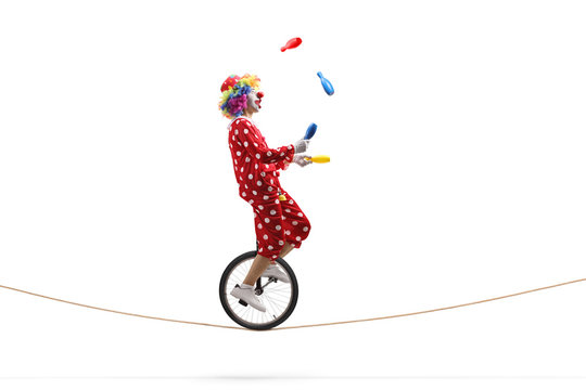 Clown Juggling With Clubs And Riding A Unicycle On A Rope