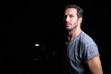 Portrait of handsome bearded man thinking outdoors at night