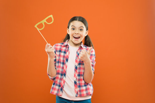 Perfect props for celebrating. Happy little child showing thumbs up hand to glasses props. Funny small girl holding glasses photobooth props on stick. Cute kid smiling with fancy party props
