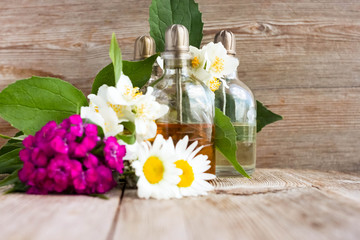 Spa perfume essential aroma oil glass bottles with flower blossoms on old wooden background