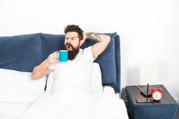 Tune in to new day. Humanity runs on coffee. Morning awakening better with cup coffee. Relax and rest. Man brutal handsome hipster relaxing bedroom drink coffee. Bearded guy enjoy morning coffee