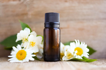 Spa perfume essential aroma oil glass bottle with flower blossoms on old wooden background