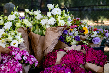 Paper-wrapped bundles of fresh summer flowers make a colorful display at a farmers market.