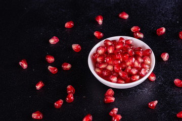 Red juice pomegranate on dark background. Ripe pomegranate with leaves on a dark background
