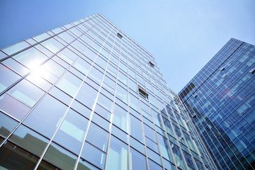 Bottom view of modern skyscrapers in business district against blue sky