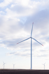 Fototapeta premium Wind turbine with cloudy sky in background