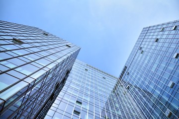 Bottom view of modern skyscrapers in business district against blue sky