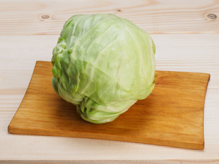Green cabbage on a cutting board on a light wooden background