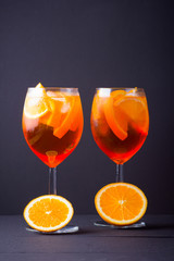 Cocktail aperol spritz on black background. Summer alcohol cocktail with orange fruit and fresh mint. Italian cocktail aperol spritz on wooden boards