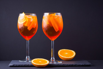 Cocktail aperol spritz on black background. Summer alcohol cocktail with orange fruit and fresh mint. Italian cocktail aperol spritz on wooden boards