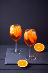 Cocktail aperol spritz on black background. Summer alcohol cocktail with orange fruit and fresh mint. Italian cocktail aperol spritz on wooden boards
