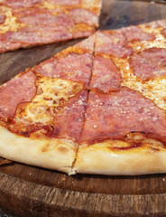 Pizza with ham on a wooden cutting Board