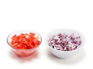 Sliced tomato and red onion in bowls on white background