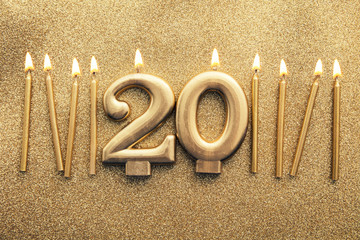 Number 20 gold celebration candle on a glitter background
