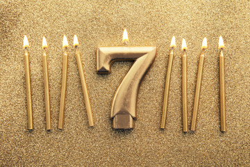 Number 7 gold celebration candle on a glitter background