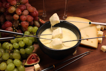 Gourmet Swiss fondue dinner on a winter evening with assorted cheeses on a board alongside a heated pot of cheese fondue