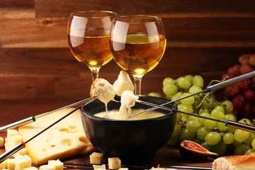 Gourmet Swiss fondue dinner on a winter evening with assorted cheeses on a board alongside a heated pot of cheese fondue