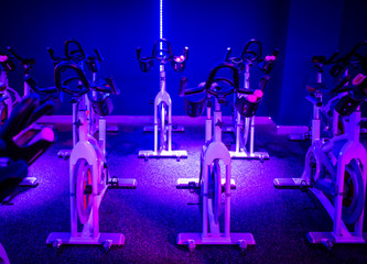 An indoor cycling dance class in a blue LED lighting room