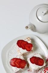 Cakes of biscuits, sour cream and strawberries. Decorated with strawberry slices. Near there is a teapot.