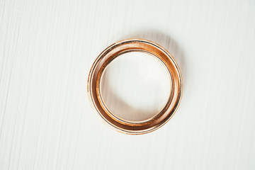 Female wedding gold ring lie in male ring in the center of white background.