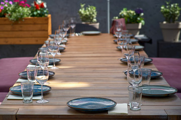 Large table on the sun terrace for guests. Blue plates and glasses on the table for restaurant visitors. Close up
