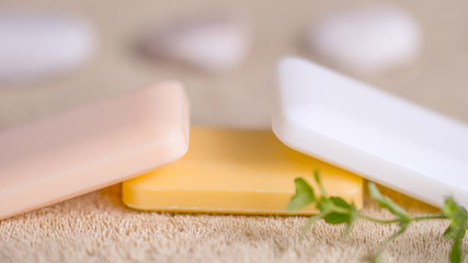 Three soap bars of pastel tones on a pale brown towel, side view