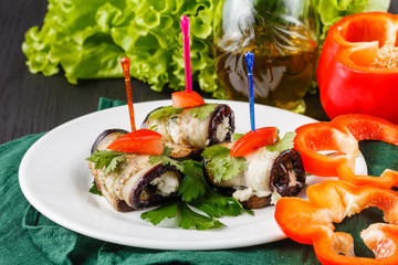 rolls of grilled slices of eggplant with feta cheese and tomato and Tzatziki sauce closeup
