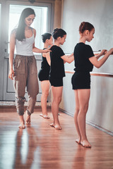 Fototapeta na wymiar Daily rehearsal of young diligent ballerinas at gymnastic school with expirienced teacher.